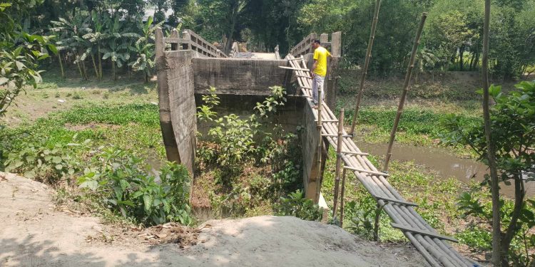 মাদারগঞ্জে ব্রীজের দুই পাশে মাটি না থাকায়, বাশের উপর দিয়ে ঝুঁকি নিয়ে পার হচ্ছে এলাকাবাসী ।